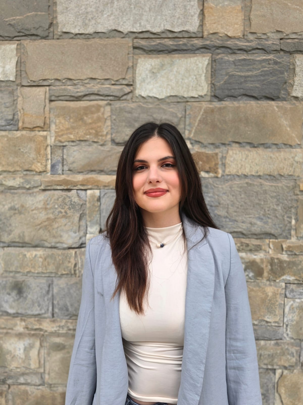 Η Ioanna Darviri όρθια μπροστά σε πέτρινο τοίχο